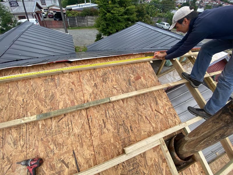 Vista aérea del equipo renovando la techumbre de una casa de madera antigua en Puerto Varas